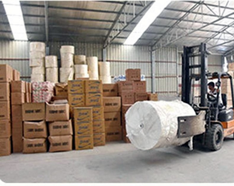 Supplier warehouse staging area with cartons, paper rolls, and forklift